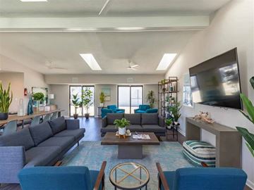 Virginia Beach apartment for rent - A living room with a grey sofa, blue chairs, and a television on the wall.