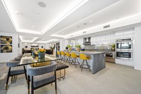 Irvine apartment for rent - the kitchen has a large island with yellow chairs and stainless steel appliances