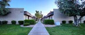 Phoenix apartment for rent - a walkway between two buildings with trees and grass on both sides of the walkway
