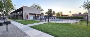 Phoenix apartment for rent - a community lawn with a pool and black metal fence and BBQ grills
