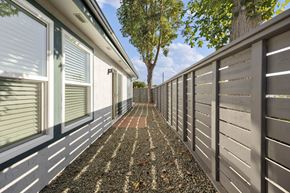 Vista apartment for rent - A long, narrow walkway between two walls with a tree in the distance.