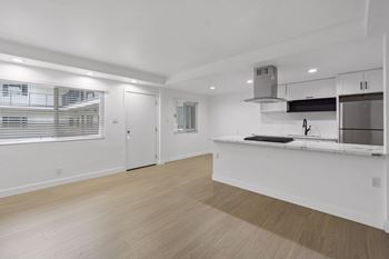 A kitchen with white cabinets and a wooden floor.