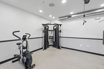 A gym room with a stationary bike and a weight machine.