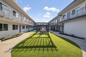 Torrance apartment for rent - the courtyard of a building with a lawn and tables and chairs at Arlington Square Apartment , Torrance