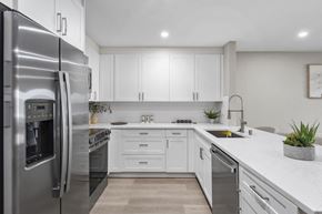 Carlsbad apartment for rent - A modern kitchen with a stainless steel refrigerator and white cabinets at Tamarack Sands Apartment Homes, California