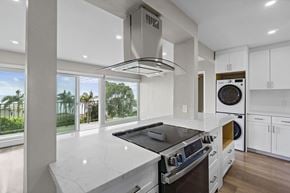 Laguna Beach apartment for rent - A modern kitchen with a stove top oven and a washing machine built into the cabinetry.at Ocean Edge @ Laguna Beach, Laguna Beach, 92651