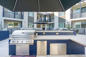 A modern outdoor kitchen with a grill and sink.