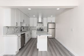 San Clemente apartment for rent - a black and white photo of a kitchen with white cabinets and stainless steel appliances at Seaview Terrace Apartment Homes, San Clemente