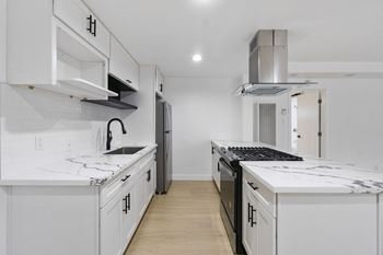 A white kitchen with a black stove top oven.