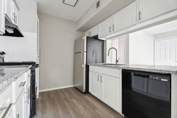 Raleigh apartment for rent - A kitchen with white cabinets and a black fridge.