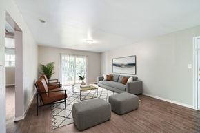 Dallas apartment for rent - A living room with a couch, chair, ottoman, and a painting on the wall.