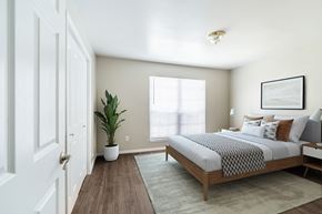 Dallas apartment for rent - A bedroom with a bed, a plant, and a framed picture on the wall.