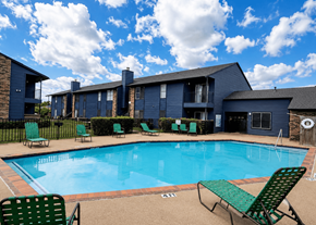 Dallas apartment for rent - A swimming pool surrounded by green chairs and a building in the background.
