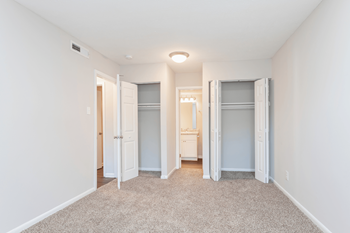 A spacious bedroom with closet doors and a carpeted floor