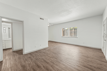 A spacious living room with white walls and wood flooring