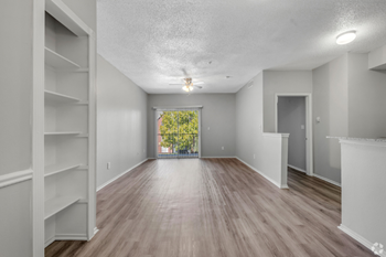 A spacious room with wooden flooring and white walls.