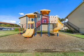 Dallas apartment for rent - A playground with a yellow slide and a red and yellow climbing structure.