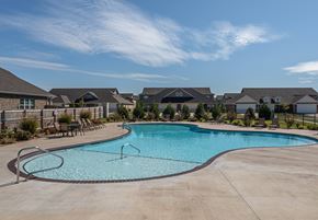 Farmington triplex for rent - A large swimming pool in a residential area with houses in the background at Cedar Crest Apartments, Farmington, AR, 72730