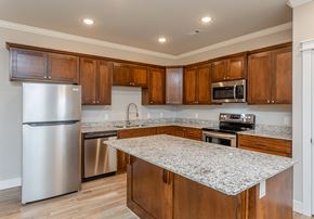 Farmington triplex for rent - A kitchen with wooden cabinets and granite countertops at Cedar Crest Apartments, Arkansas, 72730
