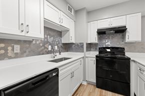Sherman apartment for rent - A kitchen with black appliances and white cabinets.at The Sidney, Texas, 75090
