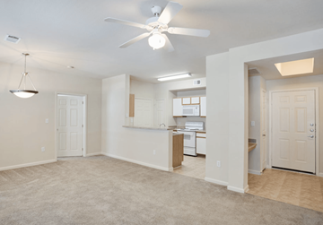 Arlington apartment for rent - A spacious room with a ceiling fan and a kitchen area in the background.