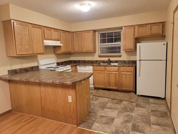 Topeka apartment for rent - a kitchen with wooden cabinets and a white refrigerator