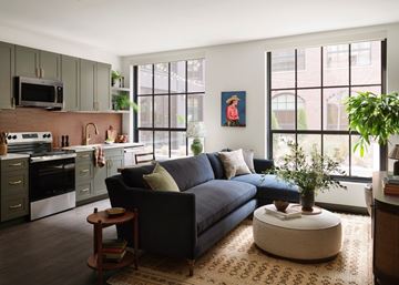 Nashville apartment for rent - A modern living room with a blue couch and a kitchen area with a microwave and oven.