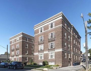 Toronto apartment for rent - A large brick building with a parking lot in front.