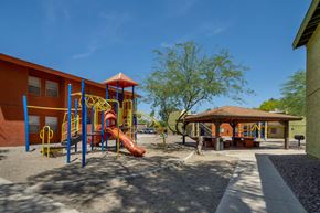 Tucson apartment for rent - A playground with a yellow slide and a brown pavilion.