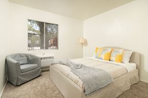 Tucson apartment for rent - A bedroom with a bed, chair, and window.