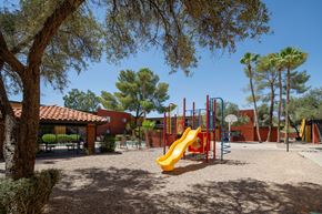 Tucson apartment for rent - A playground with a yellow slide and red and blue swings.