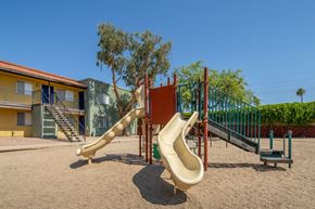 Tucson apartment for rent - A playground with a yellow slide and a green fence.