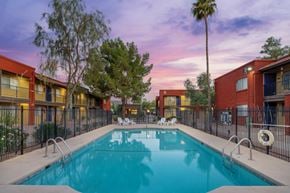 Tucson apartment for rent - A swimming pool surrounded by a fence and buildings.