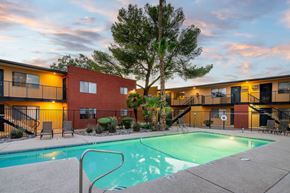 Tucson apartment for rent - A swimming pool in front of a building with a tree in the background.