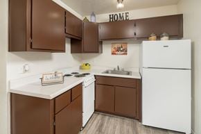 Tucson apartment for rent - A kitchen with brown cabinets and a white fridge.
