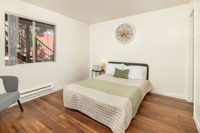 Tucson apartment for rent - A bedroom with a bed, chair, and window.