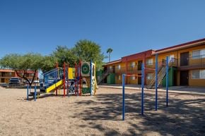Tucson apartment for rent - A playground with a slide and swings in front of a building.