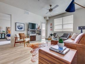 Salt Lake City apartment for rent - A living room with a brown couch, a wooden coffee table, and a ceiling fan.