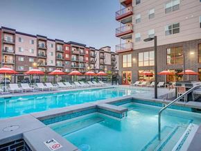 Salt Lake City apartment for rent - A swimming pool surrounded by lounge chairs and umbrellas in front of apartment buildings.