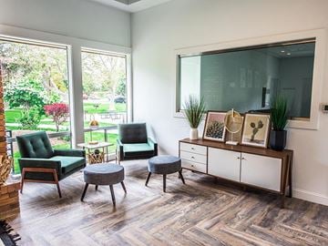Orem apartment for rent - A living room with a green chair and a grey ottoman.