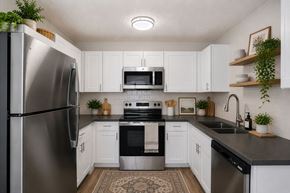 Roy apartment for rent - A kitchen with white cabinets and a black countertop.