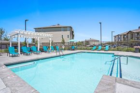 Roy apartment for rent - A swimming pool with a white pergola and blue lounge chairs.