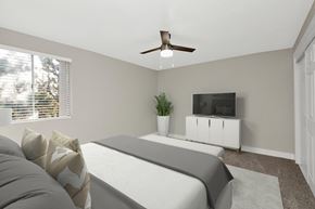 Ogden apartment for rent - A bedroom with a bed, a television, and a plant.