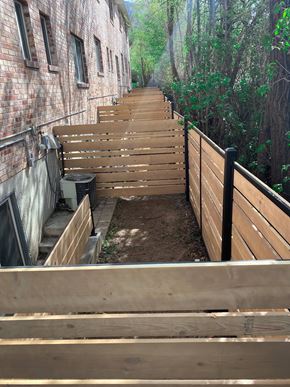 Ogden townhouse for rent - A wooden staircase with a black railing leads up to a building.
