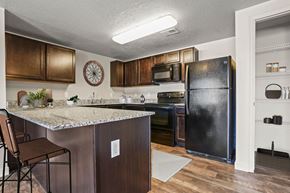 Salt Lake City apartment for rent - A kitchen with a black refrigerator and brown cabinets.