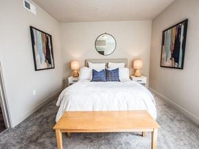 Tooele apartment for rent - A bedroom with a white bed and a wooden coffee table.