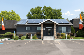 Bountiful apartment for rent - A building with solar panels on the roof and flags on the front.
