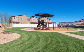 St. George townhouse for rent - A playground with a slide and a swing set in a grassy area.