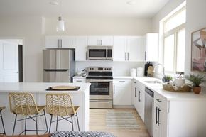 St George apartment for rent - a kitchen with white cabinets and a white island with two stools