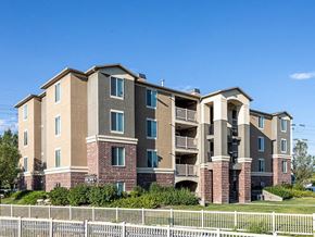 West Valley City apartment for rent - A large apartment building with a white picket fence in front.